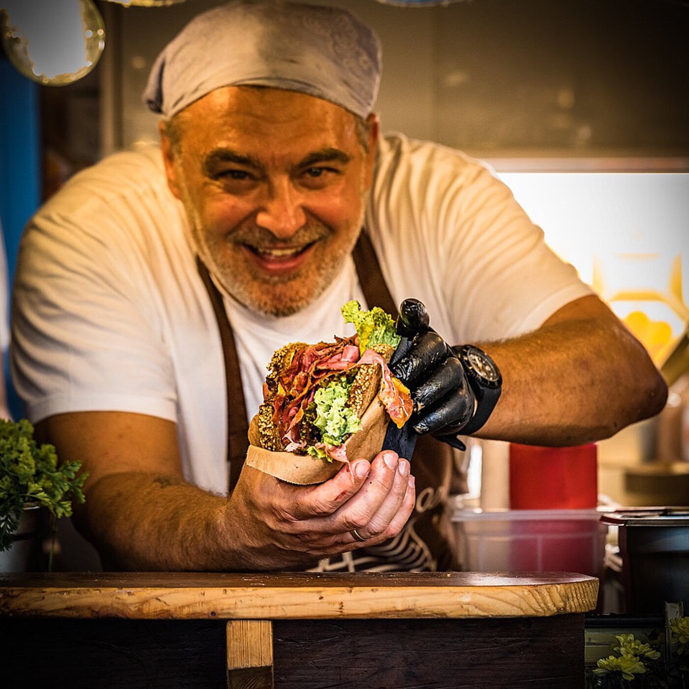 Koch hält ein frisch belegtes Pastrami-Sandwich in die Kamera